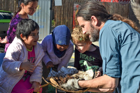 An image of a man showing compost to several children