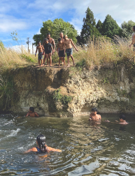 Image of several kids jumping off a bank into a river
