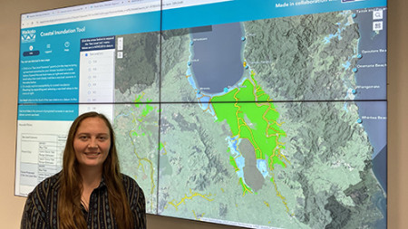 Image of a lady standing in front of tv screens showing the coastal inundation tool