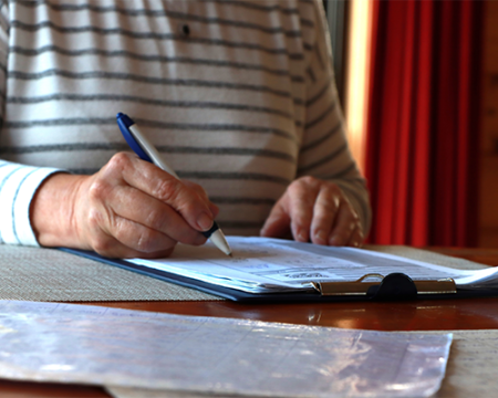 Image of someone sitting at a desk writing on a piece of paper