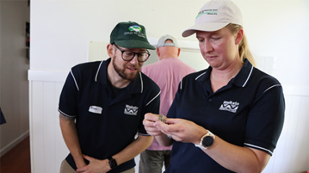 Image of two people holding a small lizard