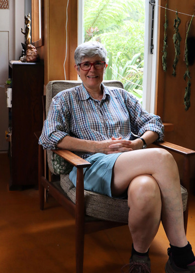 Image of a person sitting on a chair next to a window smiling