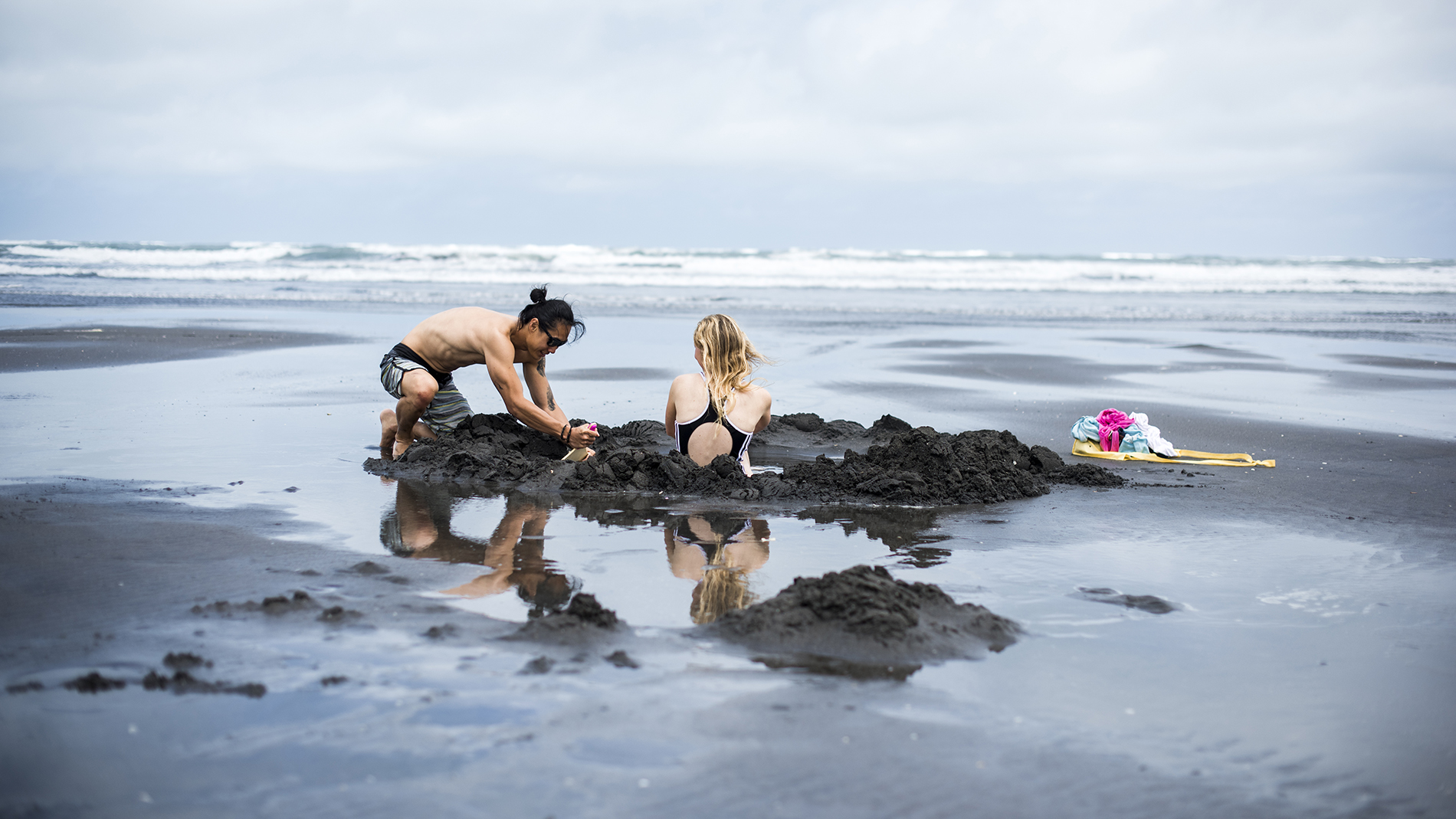 Image of two people digging a bathing hole at Hot Water Beac