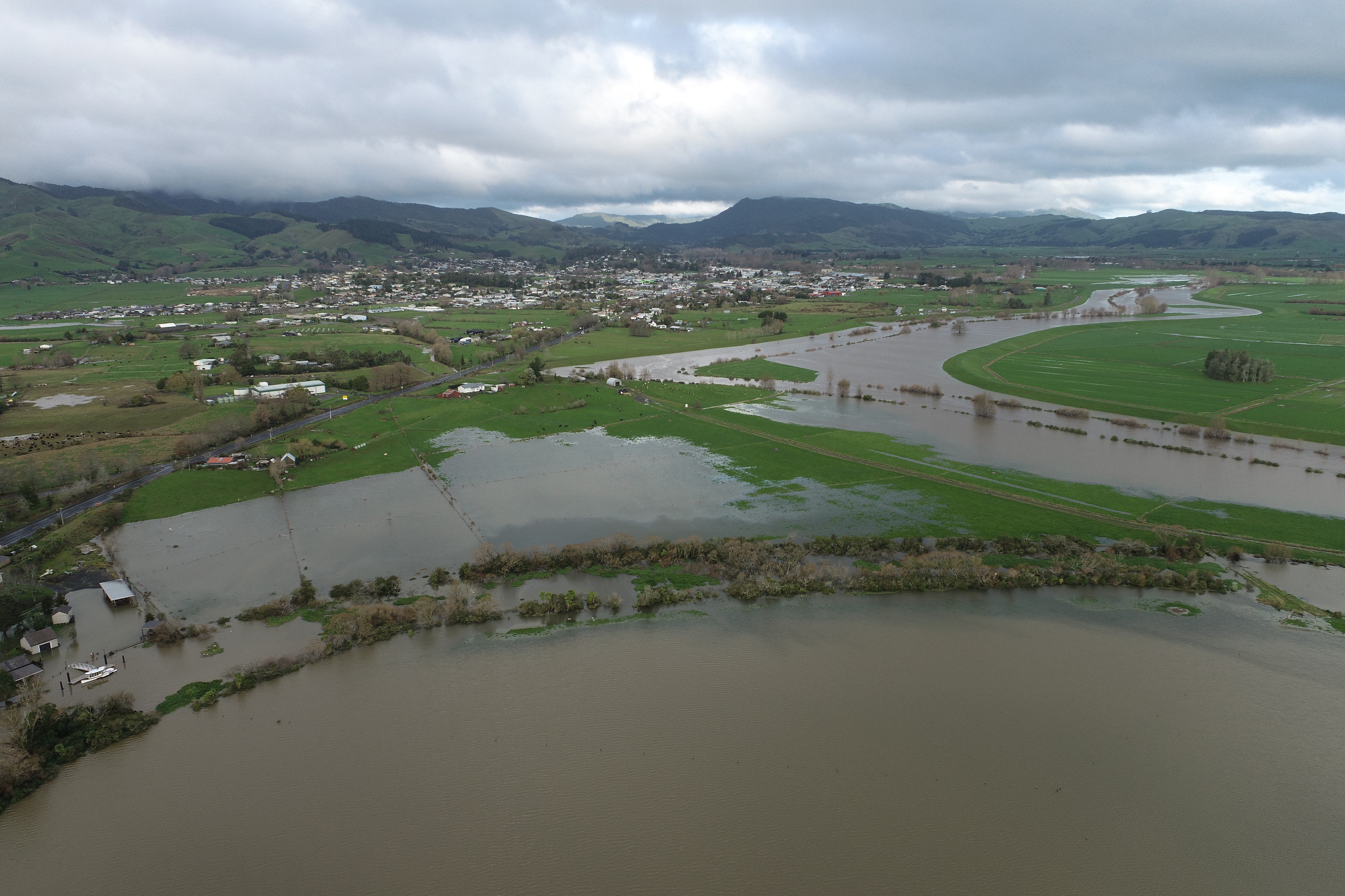 Aerial drone view of flood water spreading across farmland and a river near Paeroa